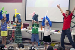 Four children hold their animal balloons up high next to Dr. Tatiana